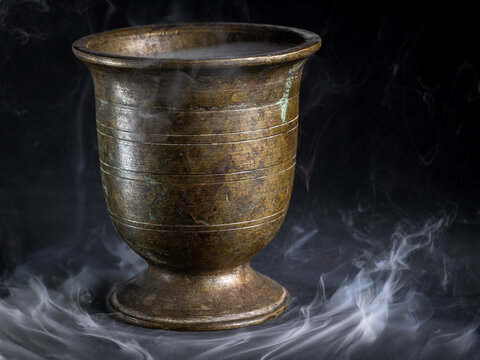 Antique bronze goblet with smoke on black background