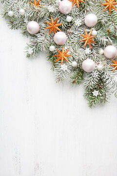 Snow-covered spruce branches  decorated with Christmas ornaments on old white wooden shabby board with empty space for text. Christmas and New Year background with holiday decorations. Flat lay