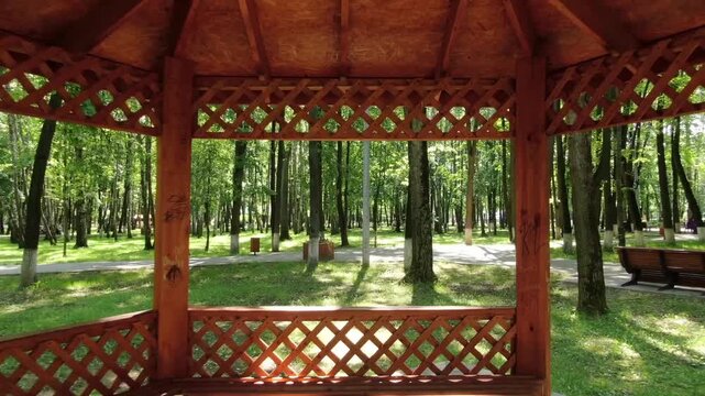 Drone flying backward from wooden gazebo in Korolev park