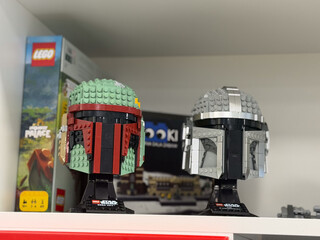 Fototapeta premium Two lego star wars helmet builds displayed on a shelf with toy boxes in the background