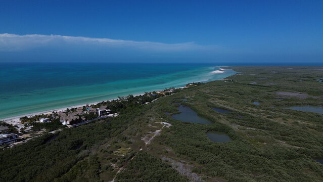 Cinematic aerial view of the lush green mangroves, emerald lagoons and wild wetlands of Holbox Island, Mexico