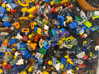 Fototapeta premium Colorful pile of assorted lego minifigure parts and accessories scattered in a mixed toy collection, viewed from above