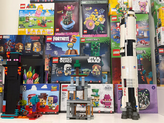 Fototapeta premium Colorful display of lego sets and built models with a tall rocket, game and movie themed boxes, arranged on shelves in a toy store