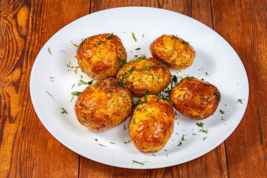 Baked young potatoes on white dish on a rustic table