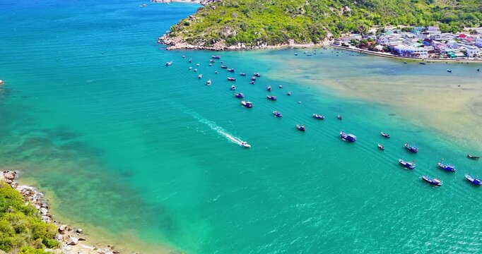 Breathtaking aerial view of Vinh Hy Bay, Vietnam, featuring emerald waters, colorful fishing boats, coastal villages, and rugged mountains
