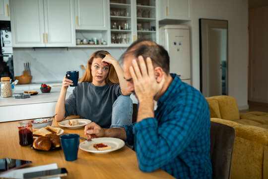 Stressed couple arguing over breakfast in home kitchen