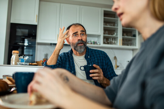 Middle-aged couple arguing over coffee in home kitchen