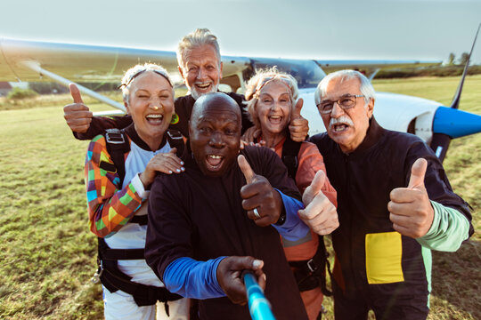 Happy senior skydivers taking selfie at airfield