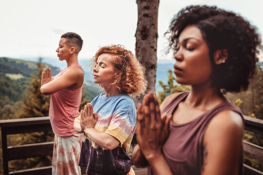 Friends practicing mindful yoga on a mountain deck