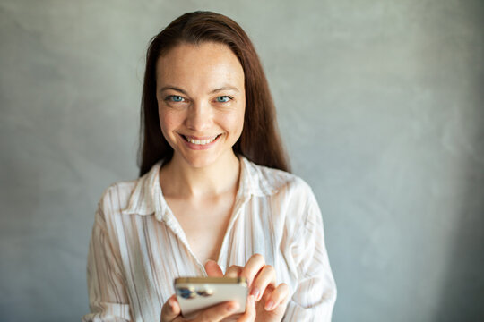 Smiling young woman using smartphone indoors