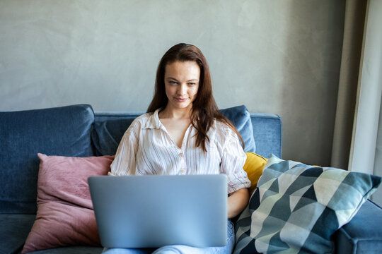 Young woman using laptop on home sofa