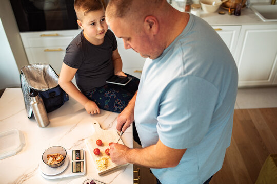 Father preparing healthy lunch with son in home kitchen