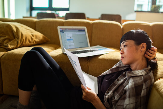 Young woman reviewing documents with laptop at home