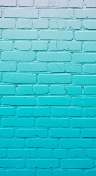 Teal brick wall with a gradient, showing texture and cracks, suitable for urban or artistic themes.