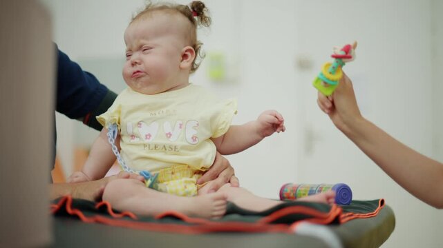 Little baby with down syndrome crying while receiving professional physical therapy, focusing on early developmental care