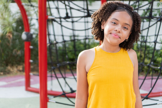 Mixed race teen girl smiling, standing in playground