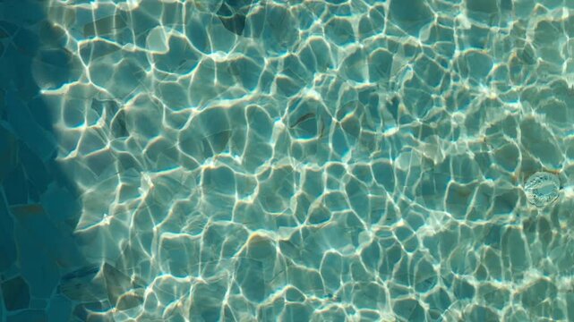 Sunlight creates moving patterns on clear blue water surface in a tranquil setting