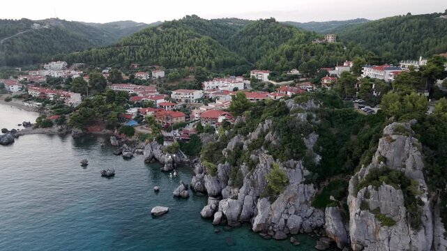 Cliffside restaurant, hotels and apartments at Loutra beach, Agia Paraskevi Pine Forest at sunset, Kassandra Peninsula, Aerial view