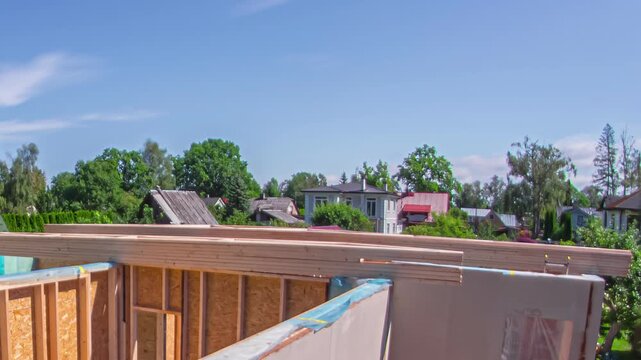 Time lapse sequence of professional workers building wooden roof frame of modern house in residential area during sunny day.
