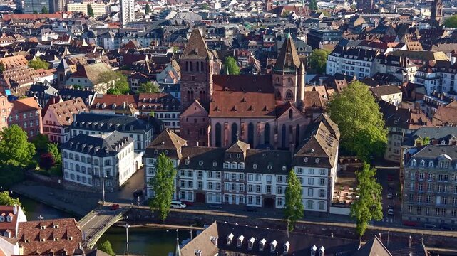 Saint Thomas church and dense traditional roofs of historic city center in Strasbourg in France. Aerial drone sideways