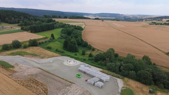 Construction site, preparation for building wind turbine farm, concrete tower section, foundation area, rows of curved segments, gravel ground in forest, Germany
