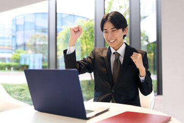 Fototapeta premium 仕事中に喜ぶアジア人ビジネスマン