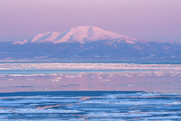 Mount Unabetsu and drift ice glowing at sunset seen from Abashiri, Hokkaido, Japan © ibuki