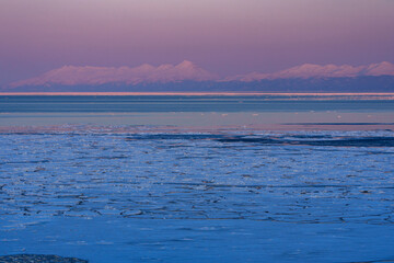Drift ice and the Shiretoko mountain range with Mount Rausu glowing at sunset seen from Abashiri, Hokkaido, Japan © ibuki