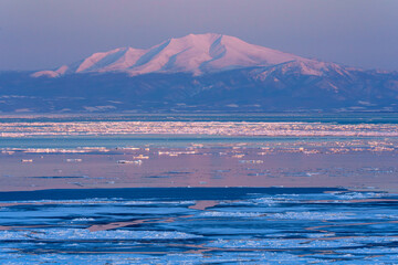 Mount Unabetsu and drift ice glowing at sunset seen from Abashiri, Hokkaido, Japan © ibuki
