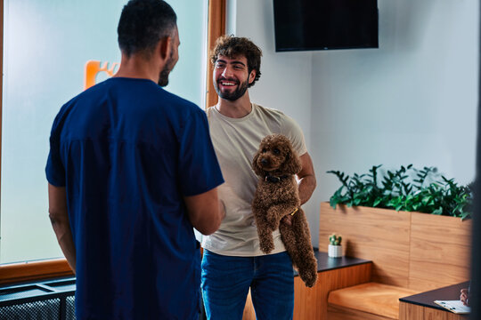 Veterinarian talking to pet owner with poodle at clinic
