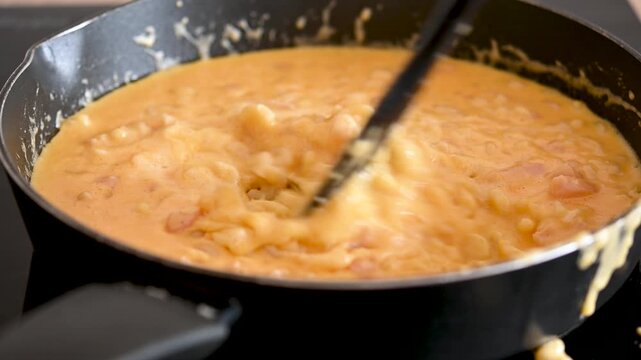 Homemade mac and cheese being stirred in a skillet
