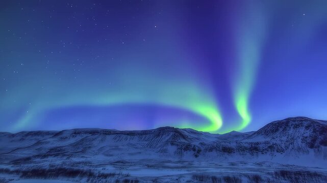 Majestic aurora borealis illuminates a snowy mountainous landscape. Green and blue hues dominate the night sky