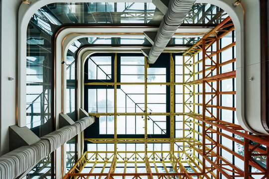 Modern Atrium Interior Looking Up Through Multiple Glass Floors with Industrial Skylight Design