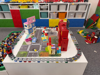 Obraz premium Colorful lego city play table in a classroom with houses, roads, cars and storage shelves in the background