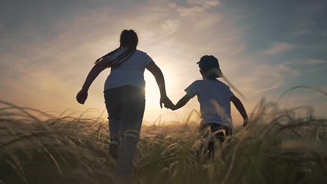 Sibling kid running fast in open field. Boy and girl laugh together. Grass around child waving in sunset. Freedom for running children. Girl runs with boy. Kid running free in warm grass sunset