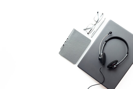 Remote customer support workspace - laptop, headset, notebook and glasses in soft natural light, top view