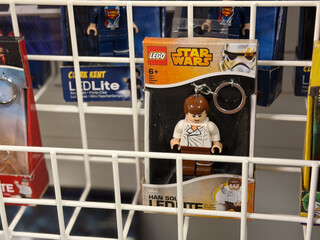 Obraz premium Lego star wars minifigure keychain displayed on a store rack with other toys and packaging in the background.
