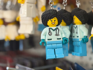Obraz premium Close-up of a toy doctor minifigure keychain hanging with blurred copies in the background, showing a playful medical theme and colorful plastic design.