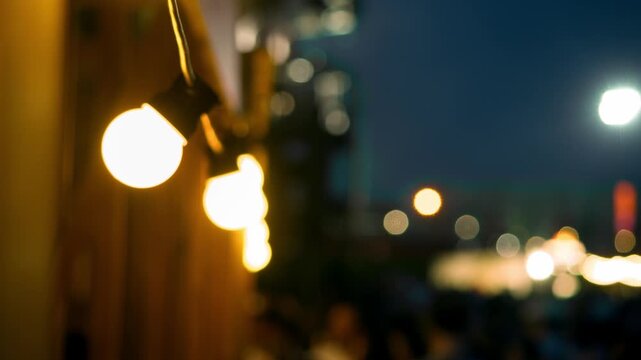 Decorative string lights illuminate outdoor music festival during warm summer night. Festive atmosphere creates inviting scene for celebration and entertainment.