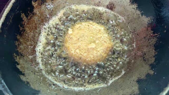 Potato cutlets frying in hot oil in a home kitchen in Dhaka, Bangladesh. Crispy homemade snack being cooked with bubbling oil during traditional meal preparation.