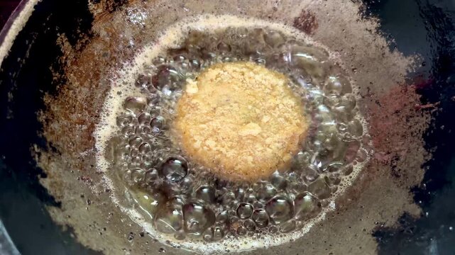 Potato fritters frying in hot oil in a home kitchen in Dhaka, Bangladesh. Crispy homemade snack cooking in a pan with bubbling oil during meal preparation.
