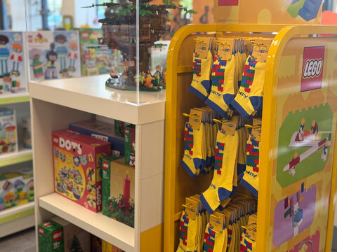 Colorful toy store display with lego socks hanging on a rack and shelves of boxed toys in the background