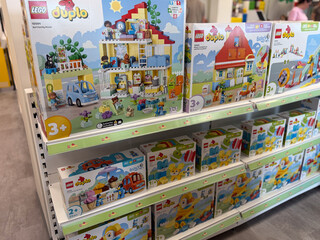 Obraz premium Colorful lego duplo toy boxes displayed on store shelves in a retail aisle, showing building sets for young children.