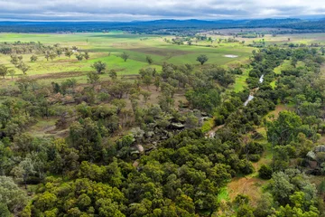 Fototapete Olive Aerial view of Reedy Creek winding through the granite rock formations and lush green bushland of Cranky Rock Nature Reserve near Warialda, NSW. The scenic landscape highlights the natural beauty  © SCLifestyle