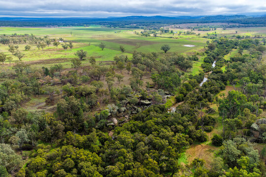 Aerial view of Reedy Creek winding through the granite rock formations and lush green bushland of Cranky Rock Nature Reserve near Warialda, NSW. The scenic landscape highlights the natural beauty