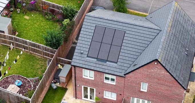 Aerial drone footage in Meanwood Leeds West Yorkshire UK focusing on modern family houses with rooftop solar panels and enclosed gardens with washing on the washing line in the summer time