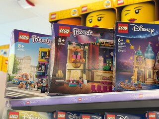 Fototapeta premium Colorful lego toy boxes displayed on a retail store shelf in a toy aisle, showing friends and disney playsets for kids and gift shopping.