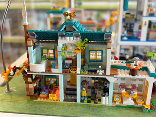Fototapeta premium Colorful miniature toy house made of building blocks displayed indoors on a table, with detailed rooms, windows, roof, and garden for creative play and collecting.