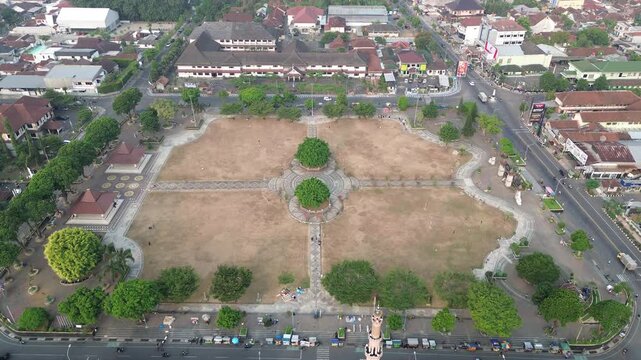 Aerial drone footage of a large open field and town square with dry brown grass due to the dry season
