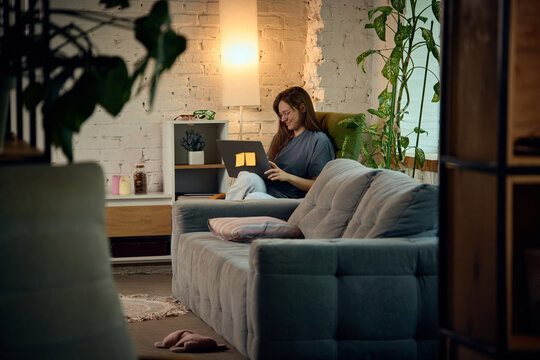 Young woman working peacefully on laptop in warm and comfortable home workspace. Concept of ecommerce management, online store operations, order processing and small business entrepreneurship.